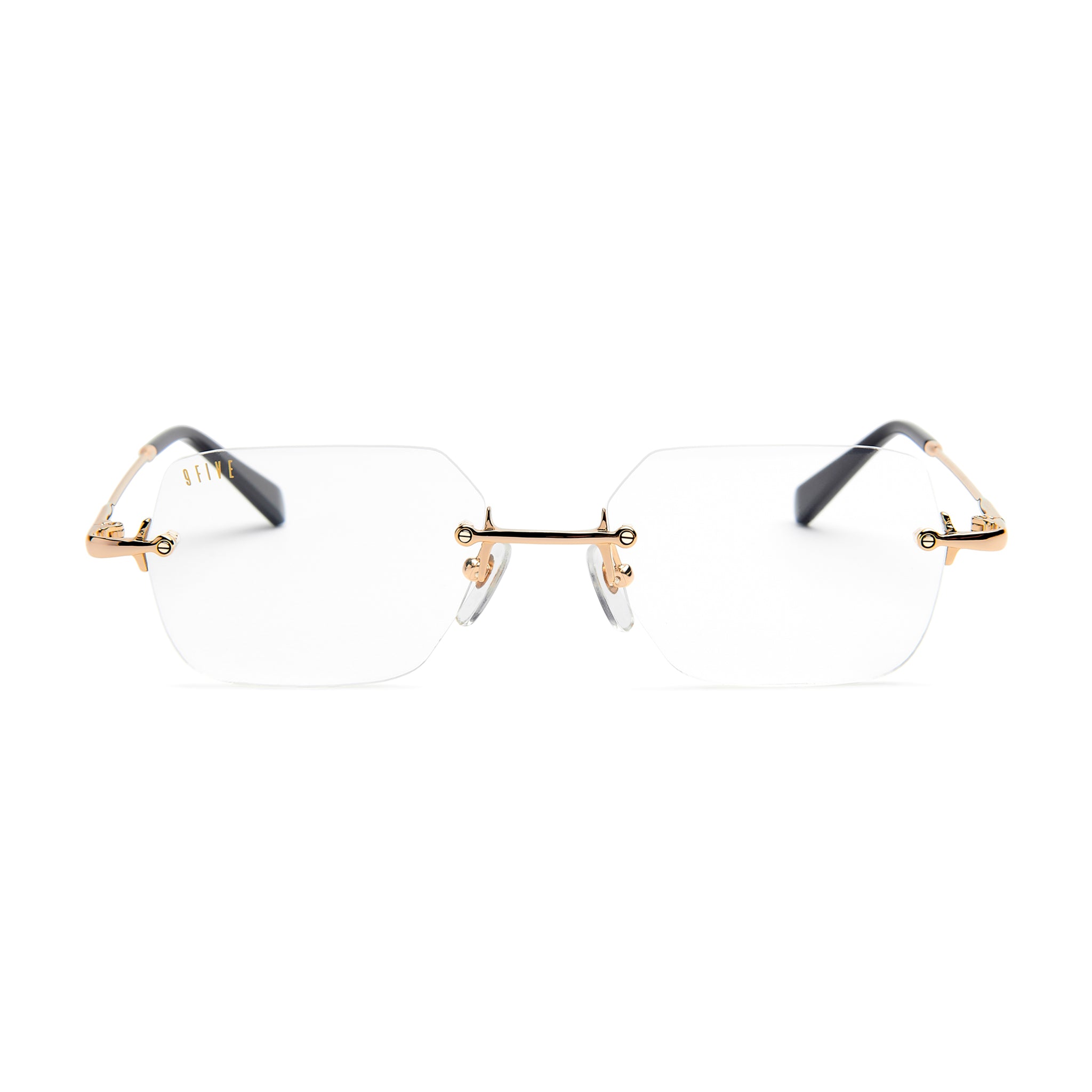 Rimless eyeglasses with clear lenses, gold metal bridge and hinges, and dark gray temple arms on a white background.