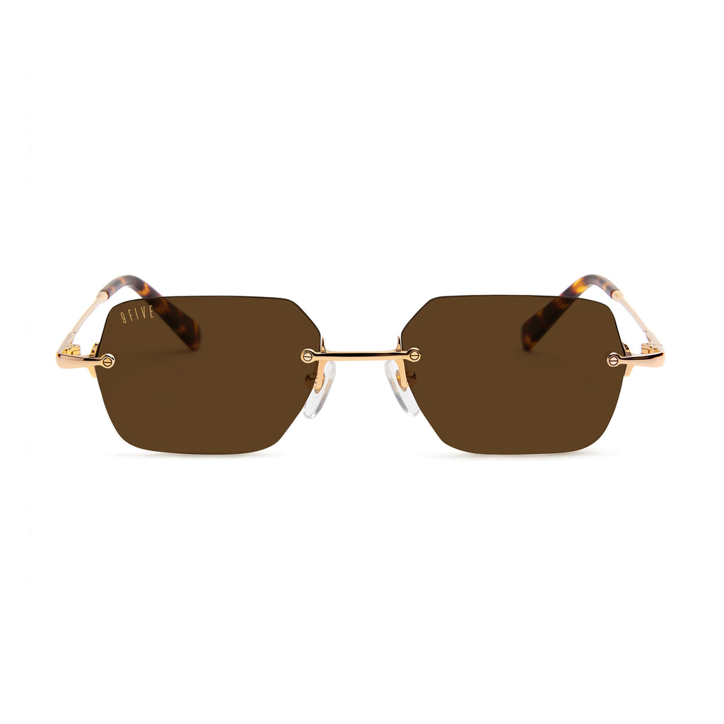 Gold-framed sunglasses with dark lenses on a beige background [g:brown s:all o:1]