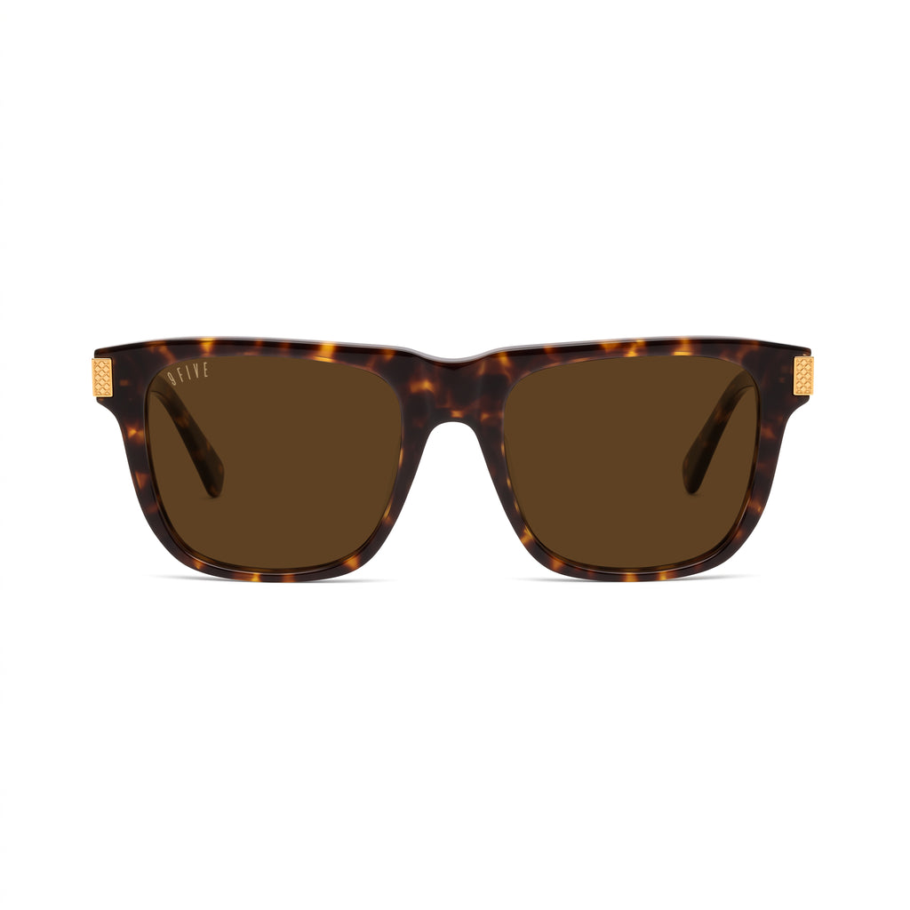Square sunglasses with a dark brown and amber tortoiseshell frame and brown lenses, featuring small gold metal accents on the temples, shown against a plain white background. [g:brown s:all o:1]