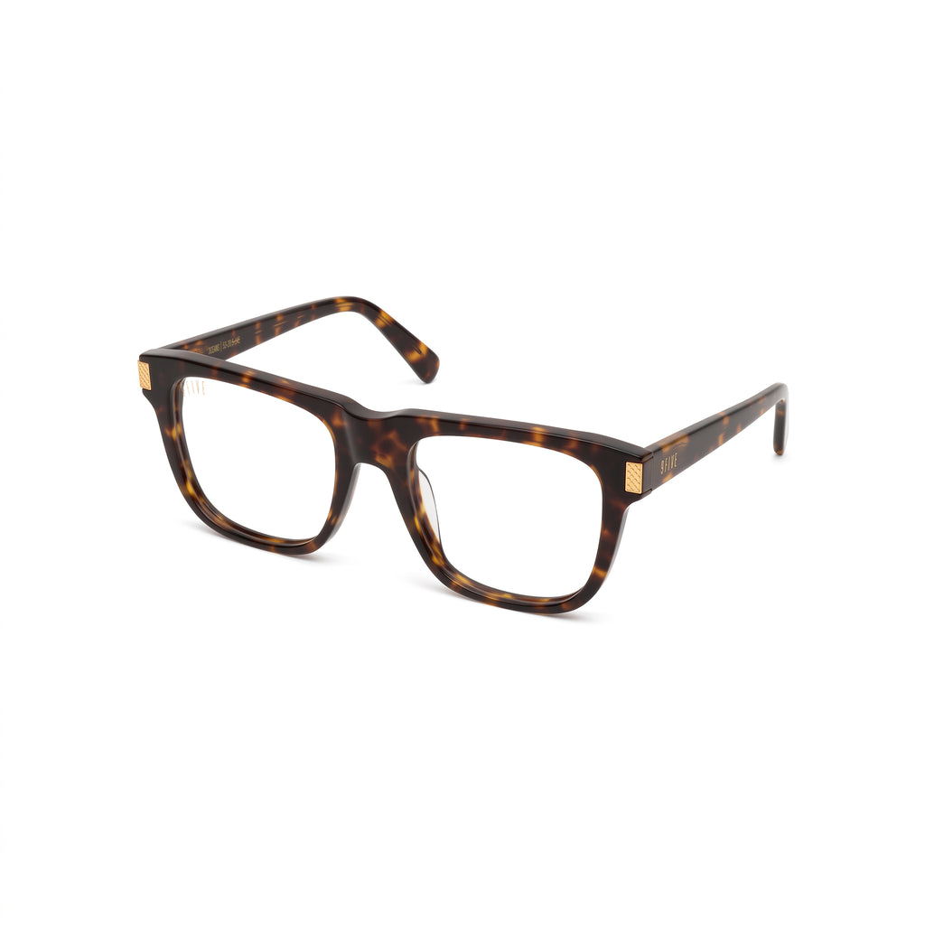 A pair of classic square-frame eyeglasses in a dark brown and amber tortoiseshell acetate, featuring small gold metal accents on the hinges and temple tips, set against a plain white background. [g:clear s:all o:2]