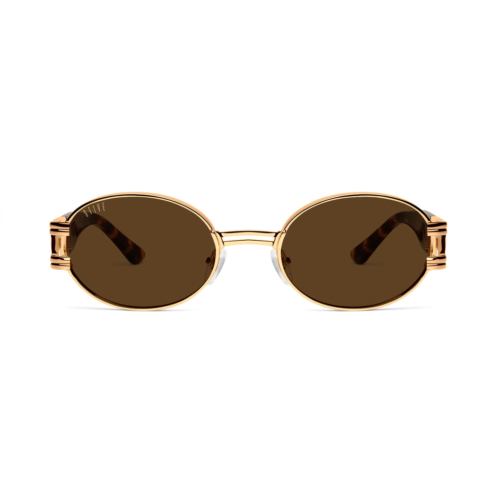 Oval sunglasses with gold metal frames, brown gradient lenses, and tortoiseshell acetate temples, shown on a clean white background. [g:brown s:all o:1]